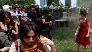 Turkish riot policeman uses tear gas during a protest in central Istanbul