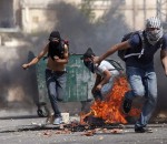 Masked Palestinians take cover before to throw stones toward Israeli soldiers near the Jewish West Bank settlement Beit El, north of Ramallah on October 5, 2025 as violence spiked in east Jerusalem and the occupied West Bank. There have been fears that the sporadic violence could spin out of control, with some warning of the risk of a third Palestinian intifada, or uprising. AFP PHOTO / ABBAS MOMANI        (Photo credit should read ABBAS MOMANI/AFP/Getty Images)